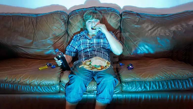 کودک در حال خوردن غذای غیرسالم و تماشای تلویزیون