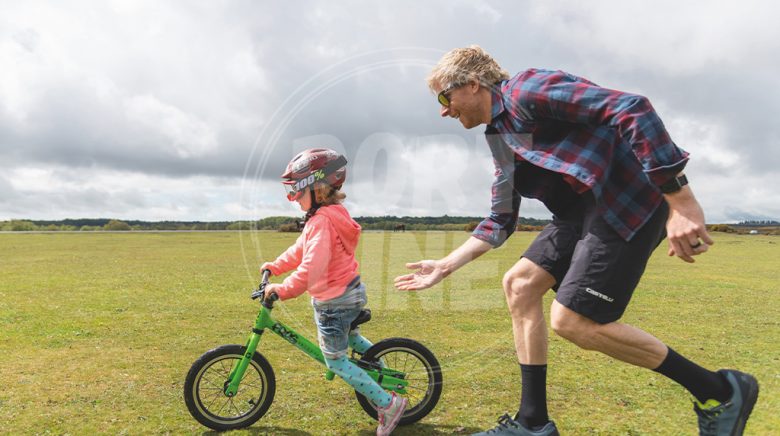 پدر در حال آموزش دوچرخه سواری به کودک