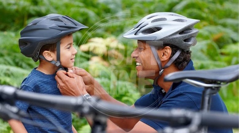 پدر در حال بستن کلاه دوچرخه سواری  برای کودک